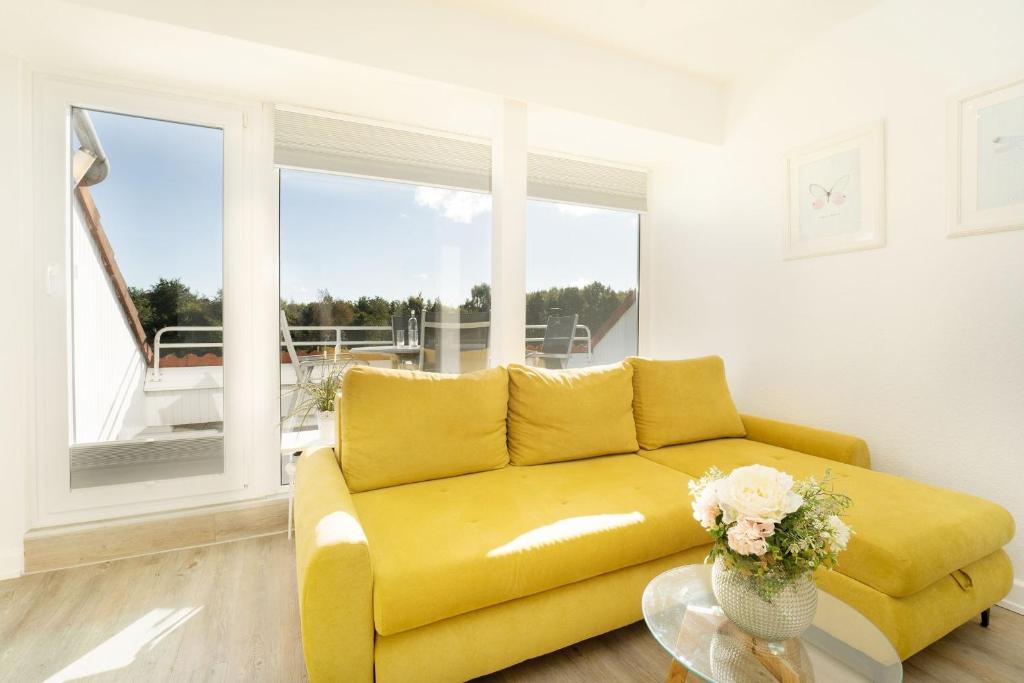 a yellow couch in a living room with a window at Golfresidenz Ostseebude in Grömitz