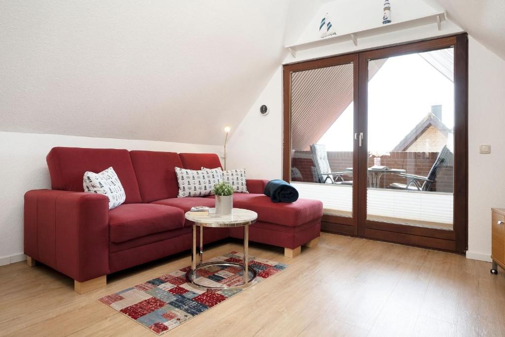 a living room with a red couch and a table at Hasenkamp 18 Krabbe in Grömitz