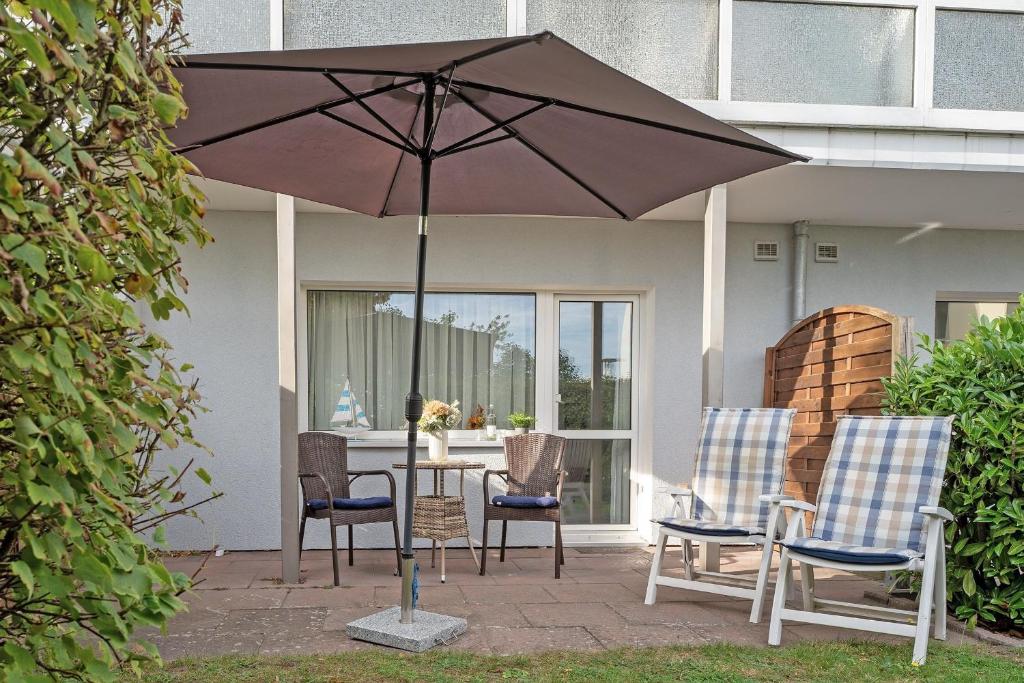 a table with chairs and an umbrella on a patio at Seepferdchen Urlaubstied in Hansaland