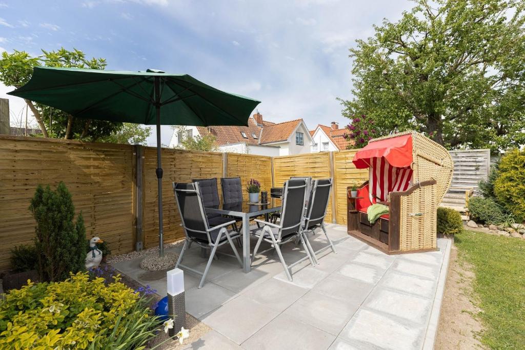 un patio avec une table, des chaises et un parasol dans l'établissement Ferienhaus Freitag, à Kellenhusen