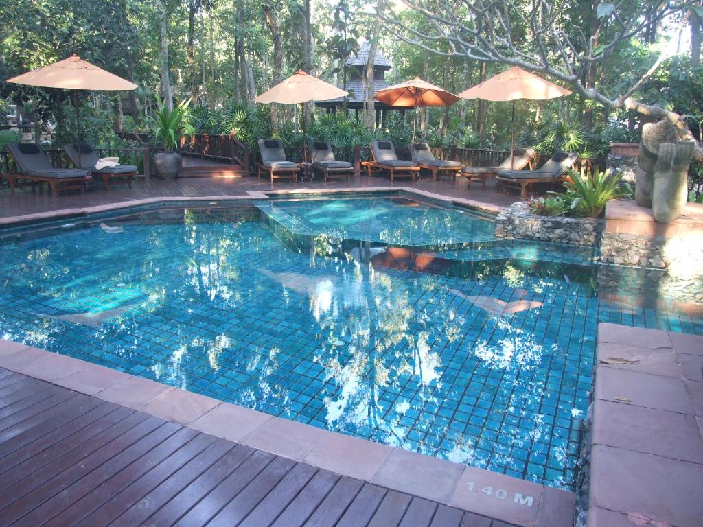 a pool with chairs and umbrellas on a wooden deck at Residence 7 at the Four Seasons Resort in Mae Rim