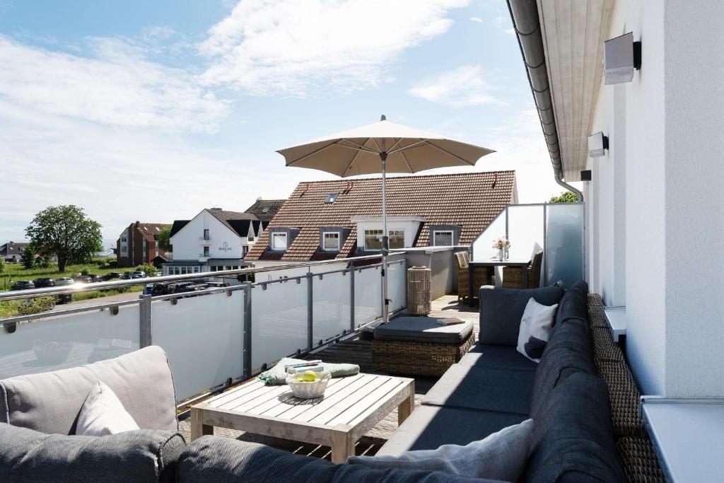 a balcony with a couch and an umbrella at Ostseedomizil Beachloft in Kellenhusen