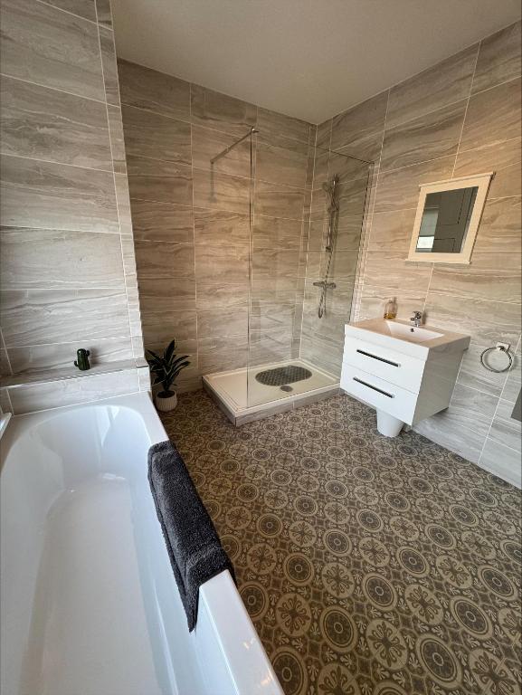 a bathroom with a tub and a shower and a sink at Valletta House Holiday Apartments in Skegness