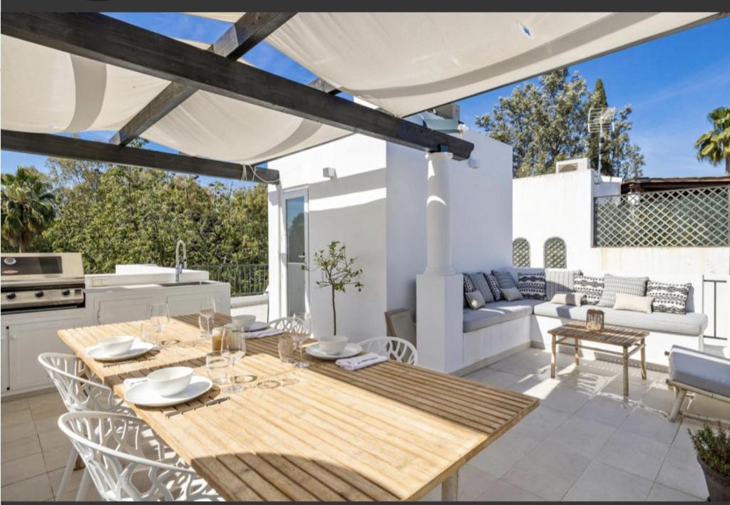 eine Terrasse mit einem Holztisch und Stühlen in der Unterkunft SE8 - Stylish townhouse with rooftop terrace in Marbella