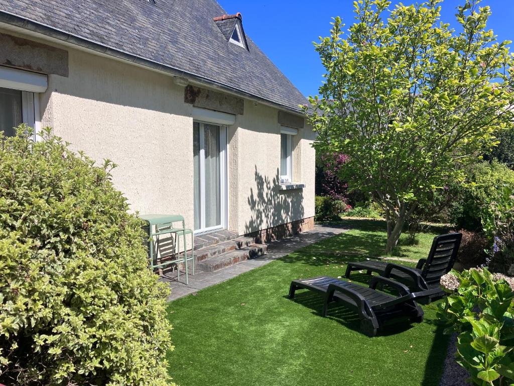 a yard with two black chairs in the grass at Maison au calme rénovée plain-pied, hyper centre ville Perros in Perros-Guirec