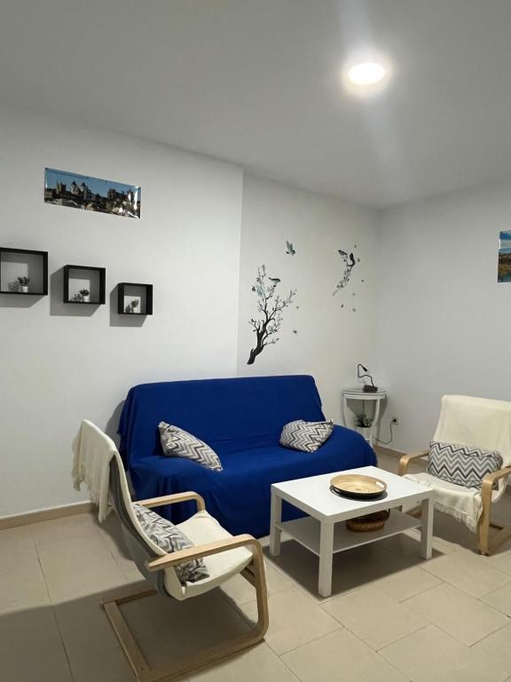 a living room with a blue couch and two chairs at Casa 22 in Plasencia