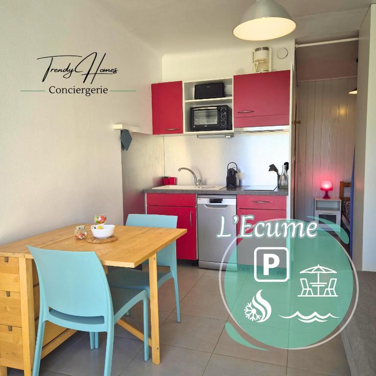 - une cuisine avec des placards rouges, une table et des chaises en bois dans l'établissement L'ECUME - Logement les pieds dans le sable, à Mauguio