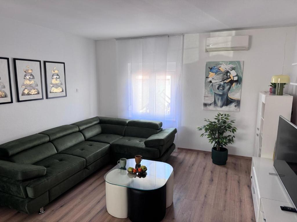 a living room with a green couch and a coffee table at Apartman Mia Bibinje in Bibinje