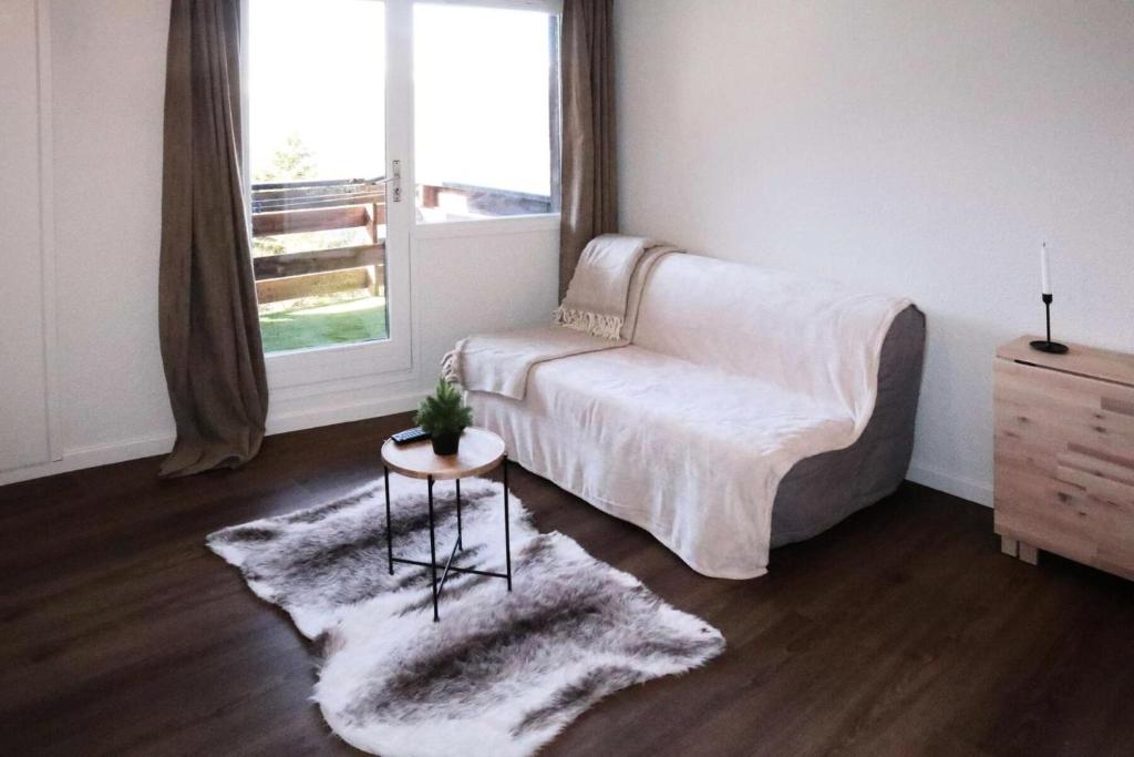 - un salon avec un canapé blanc et une fenêtre dans l'établissement Résidence Le Cairn - Studio pour 4 personnes MAE-2041, aux Orres