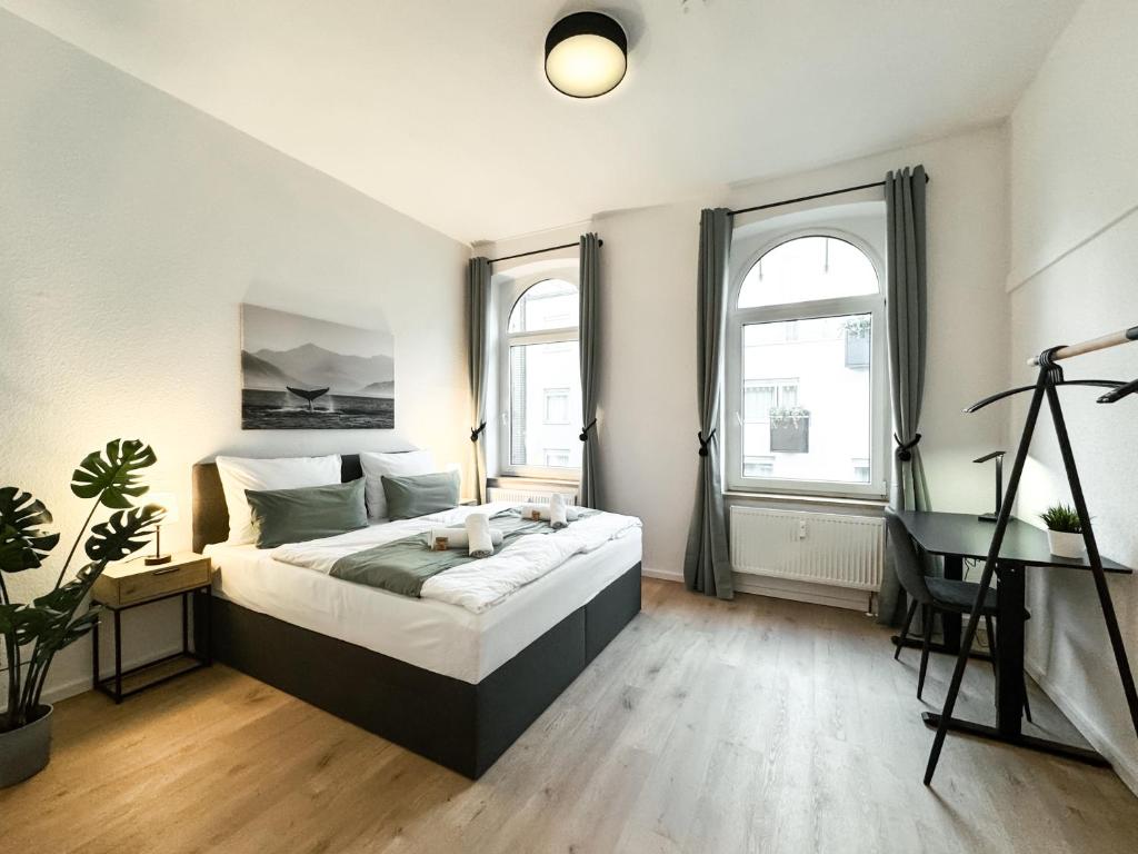 a bedroom with a bed and a desk and two windows at Stobbe Stays I Zentral I Parkplatz I Kingsize I 116qm in Hannover