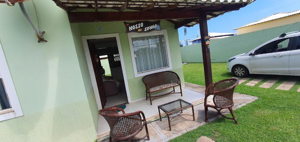 eine Terrasse mit drei Stühlen und einem Tisch und einem Auto in der Unterkunft casa dois quartos completa em saquarema, barra nova in Saquarema