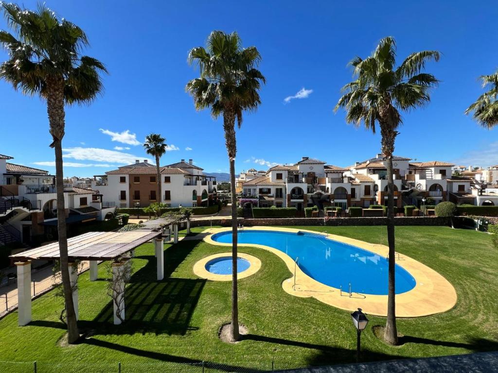 una vista di una piscina con palme e case di El Ático de Vera a Vera