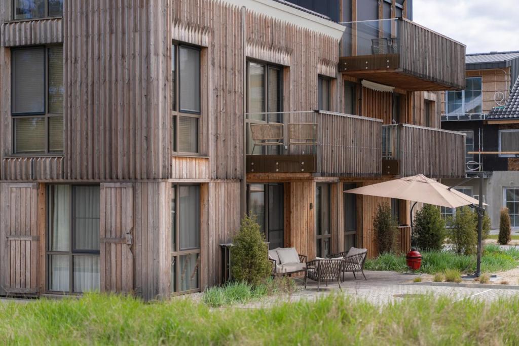 an apartment building with a patio and an umbrella at Debesu kopa in Nida