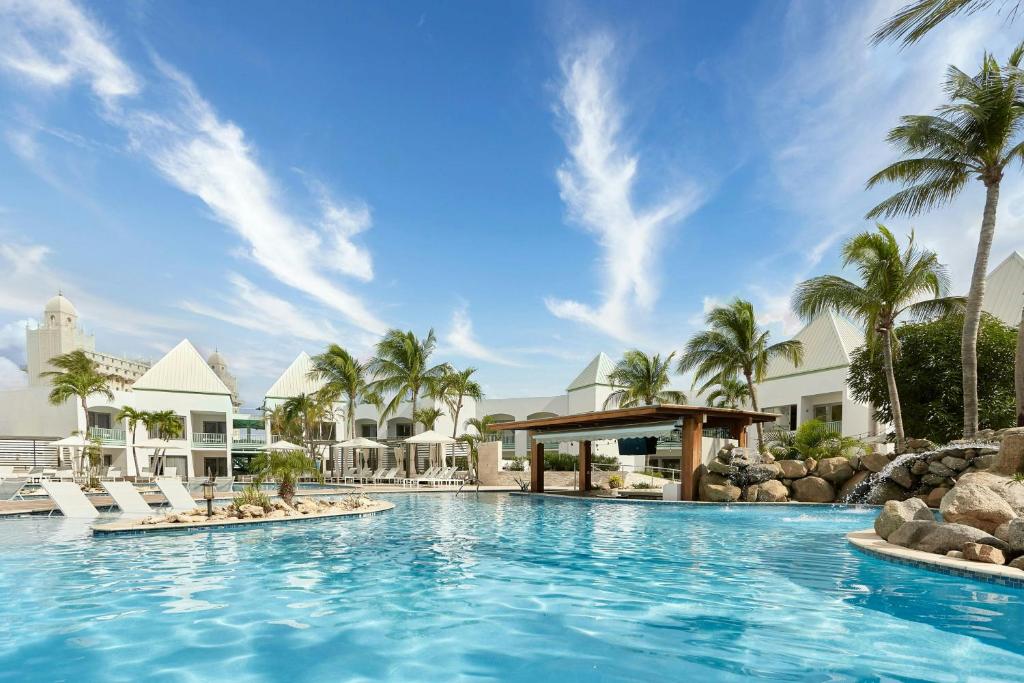 einen Pool in einem Resort mit Palmen in der Unterkunft Courtyard by Marriott Aruba Resort in Palm-Eagle Beach