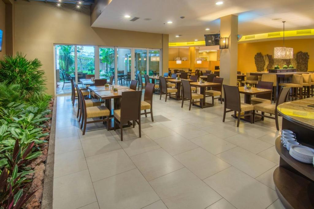 a dining room with tables and chairs in a restaurant at Courtyard by Marriott San Jose Airport Alajuela in Alajuela City