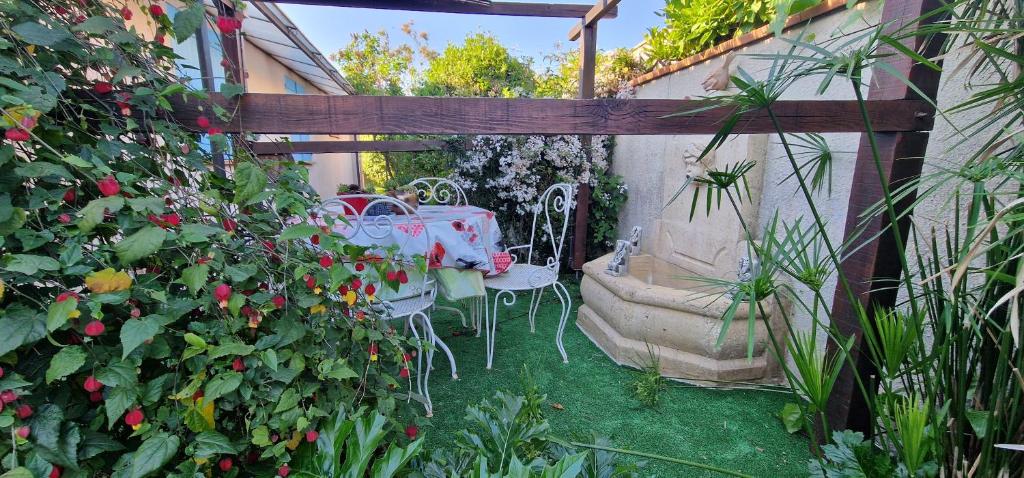 une table et des chaises dans un jardin orné de roses dans l'établissement Très jolie maison Languedocienne, au Cap d'Agde