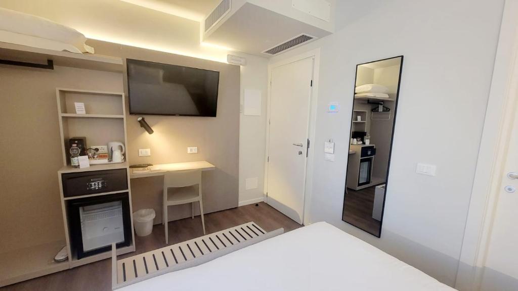 a room with a bed and a television and a desk at Hotel Aurora Duino in Duino