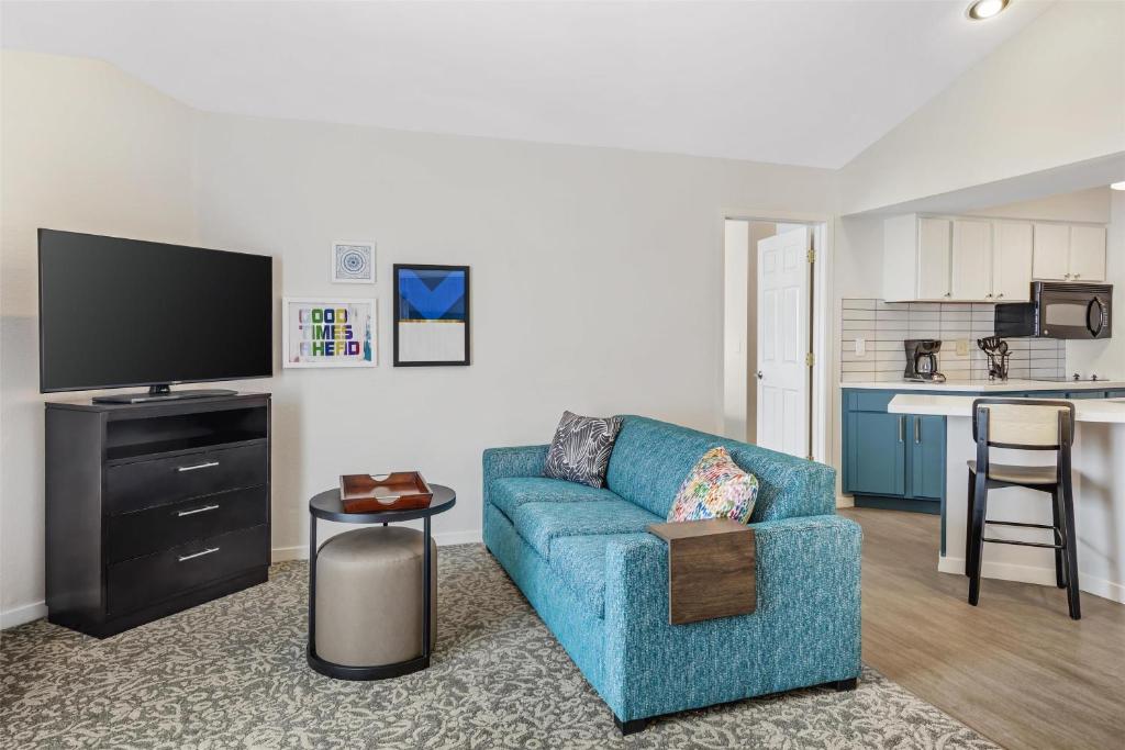 Una sala de estar con un sofá azul y una cocina. en Sonesta ES Suites Chatsworth, en Chatsworth