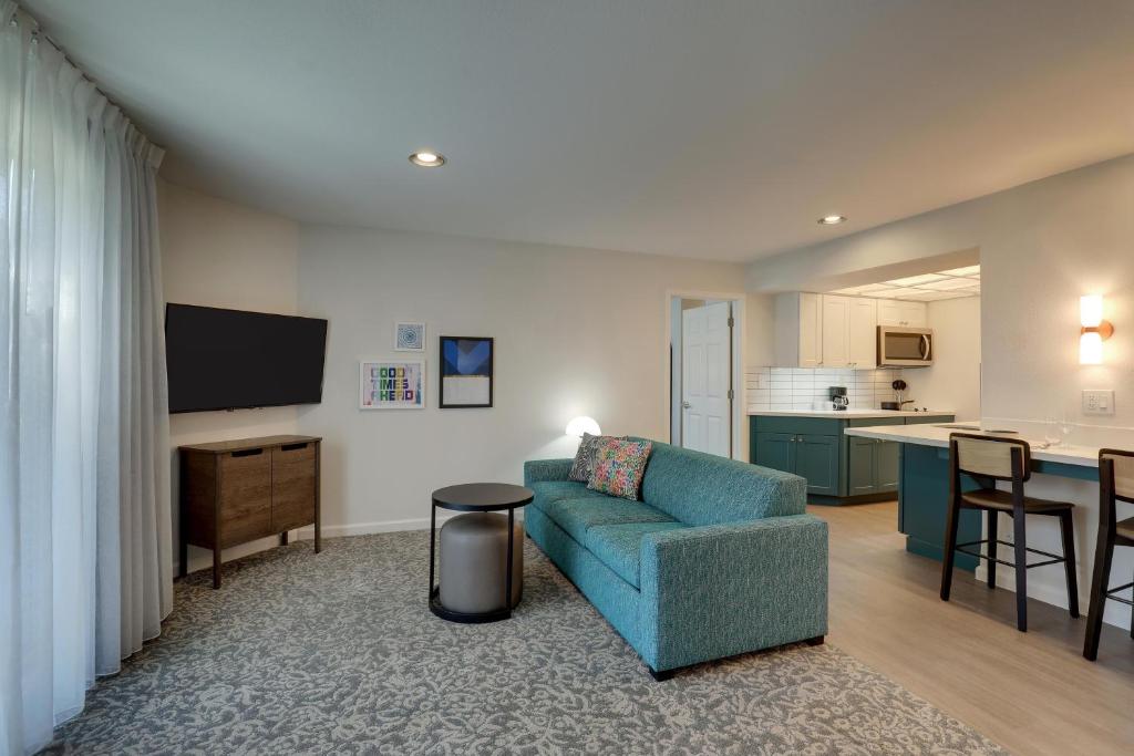a living room with a blue couch and a kitchen at Sonesta ES Suites San Jose - Airport in San Jose