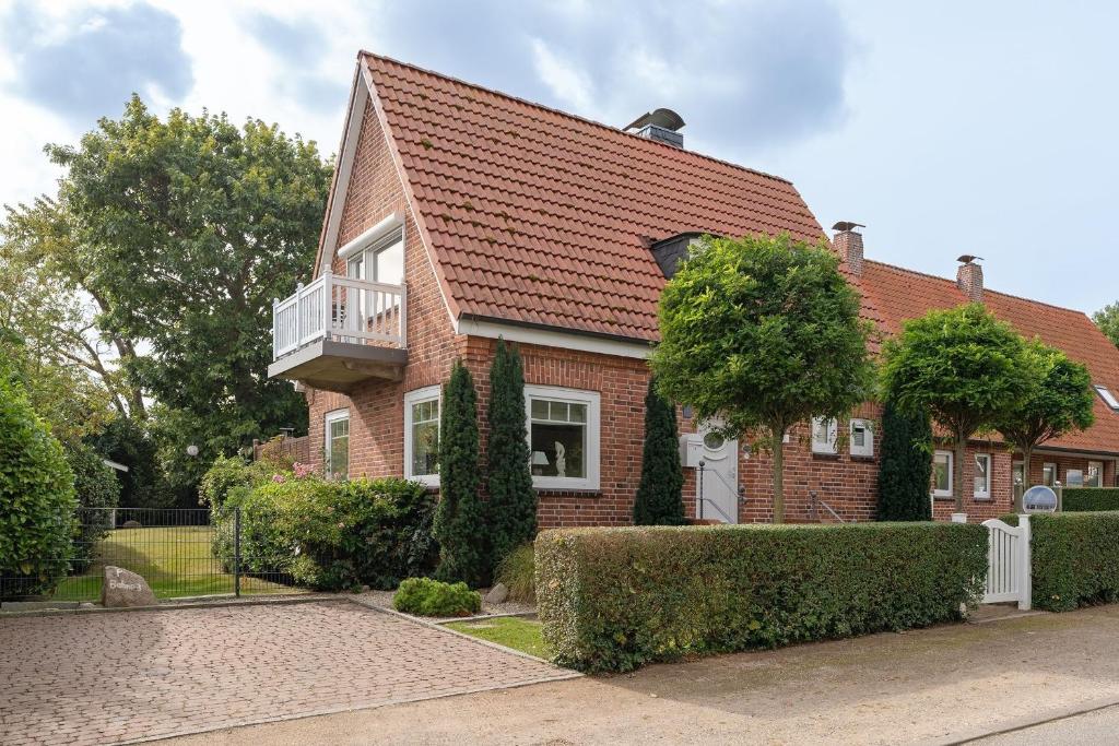 a red brick house with a balcony and bushes at Buhne 3 in Grömitz