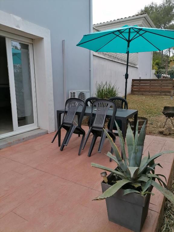 un patio avec une table, des chaises et un parasol dans l'établissement Gite MARTIN, à Grabels