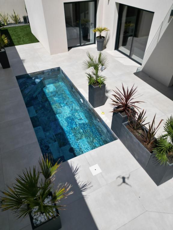 an overhead view of a swimming pool with plants at La villa Kalima T3 in Sérignan