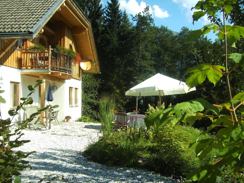 a house with a balcony and an umbrella at Ferienwohnung Waldhauser in Hermagor