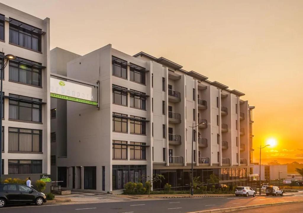 a large white building with a sunset in the background at Cosy Urban Apartment in Durban