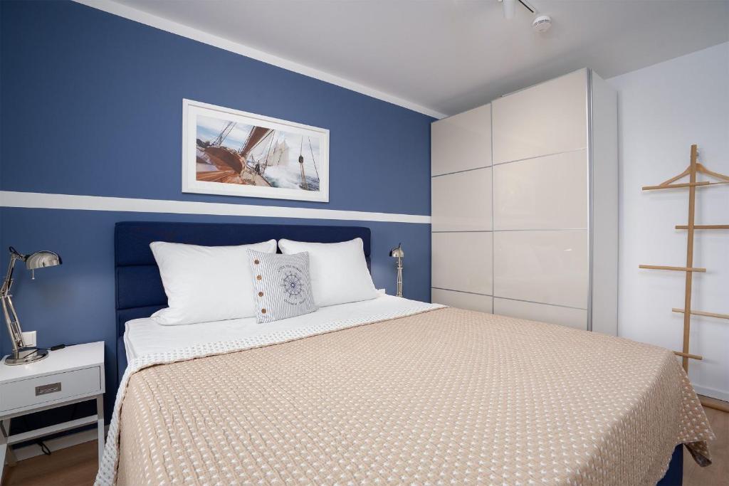 a bedroom with blue walls and a bed with white pillows at Hauptstraße 26e Deck 9 in Timmendorfer Strand