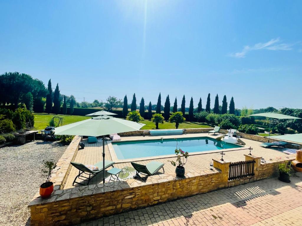 une piscine avec deux chaises et un parasol dans l'établissement Domaine du ValféEric, à Saint-Sulpice-dʼExcideuil