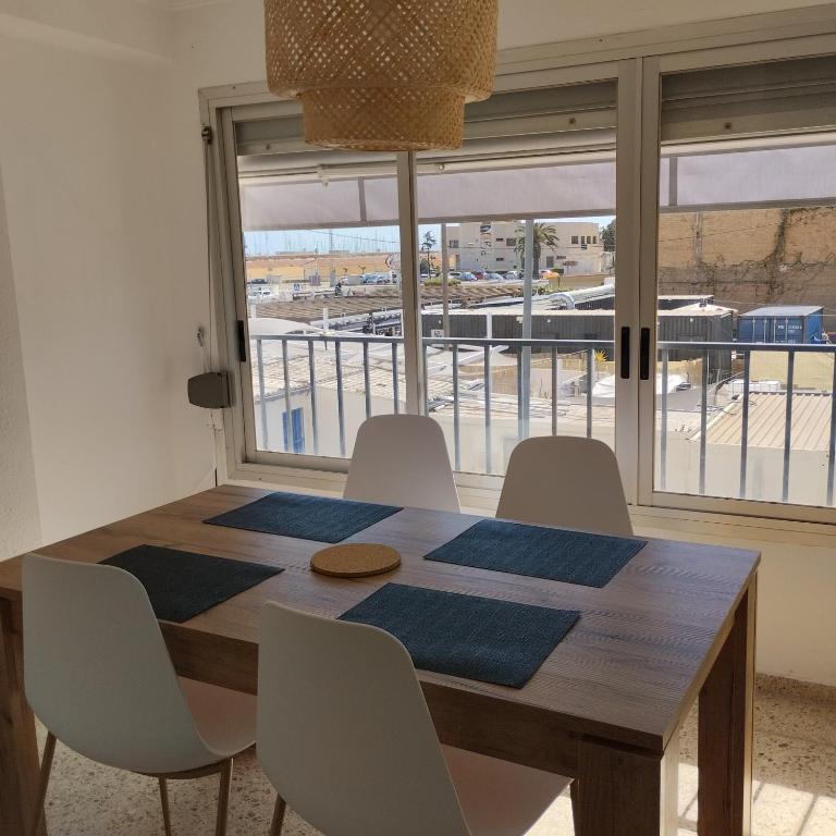 a dining room table with white chairs and a large window at Burrianna Beach Apartment in Burriana