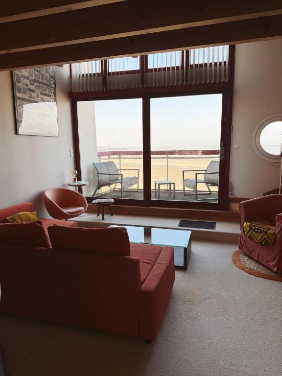 un salon avec un canapé et une grande fenêtre dans l'établissement Sur le pont d un bateau à Boulogne sur Mer, à La Celle-sous-Gouzon