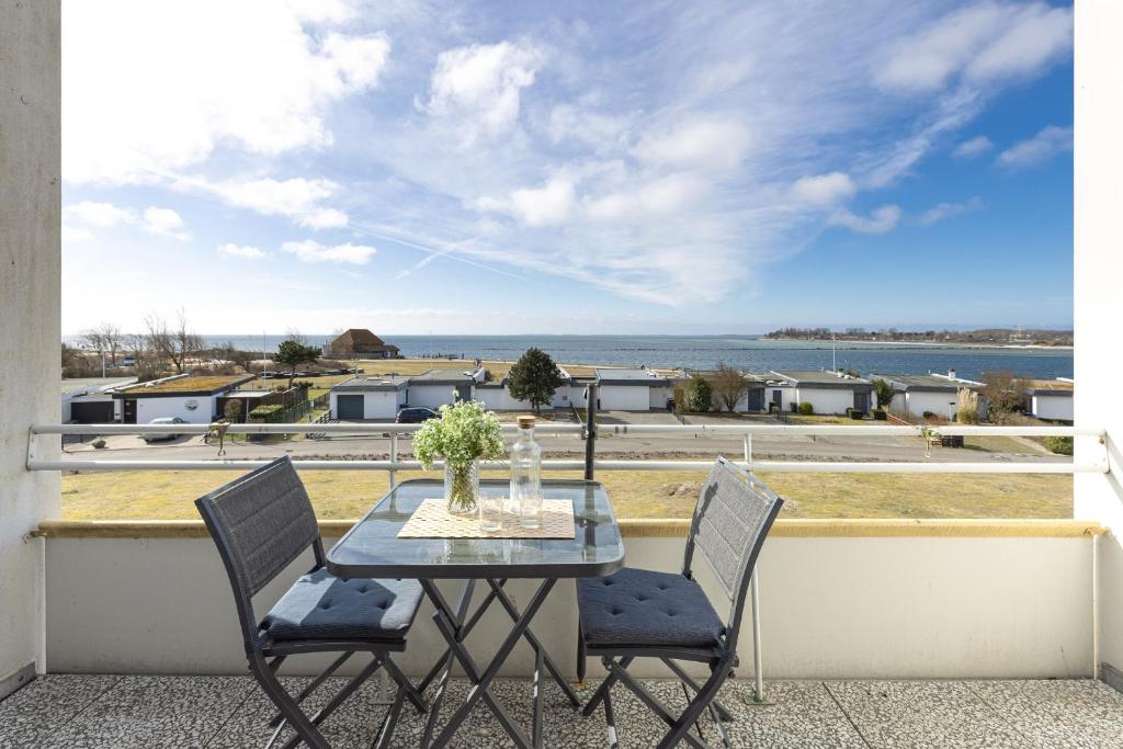 a table and chairs on a balcony with a view of the ocean at StrandMöwe in Burgtiefe auf Fehmarn 