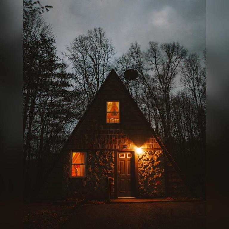 a cabin lit up at night with a light at the door at A-Frame #07 - by The Chalets in Logan