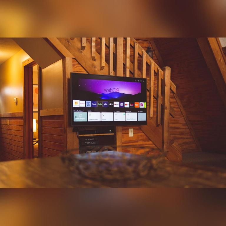 a flat screen tv in a room with a staircase at A-Frame #08 - by The Chalets in Logan