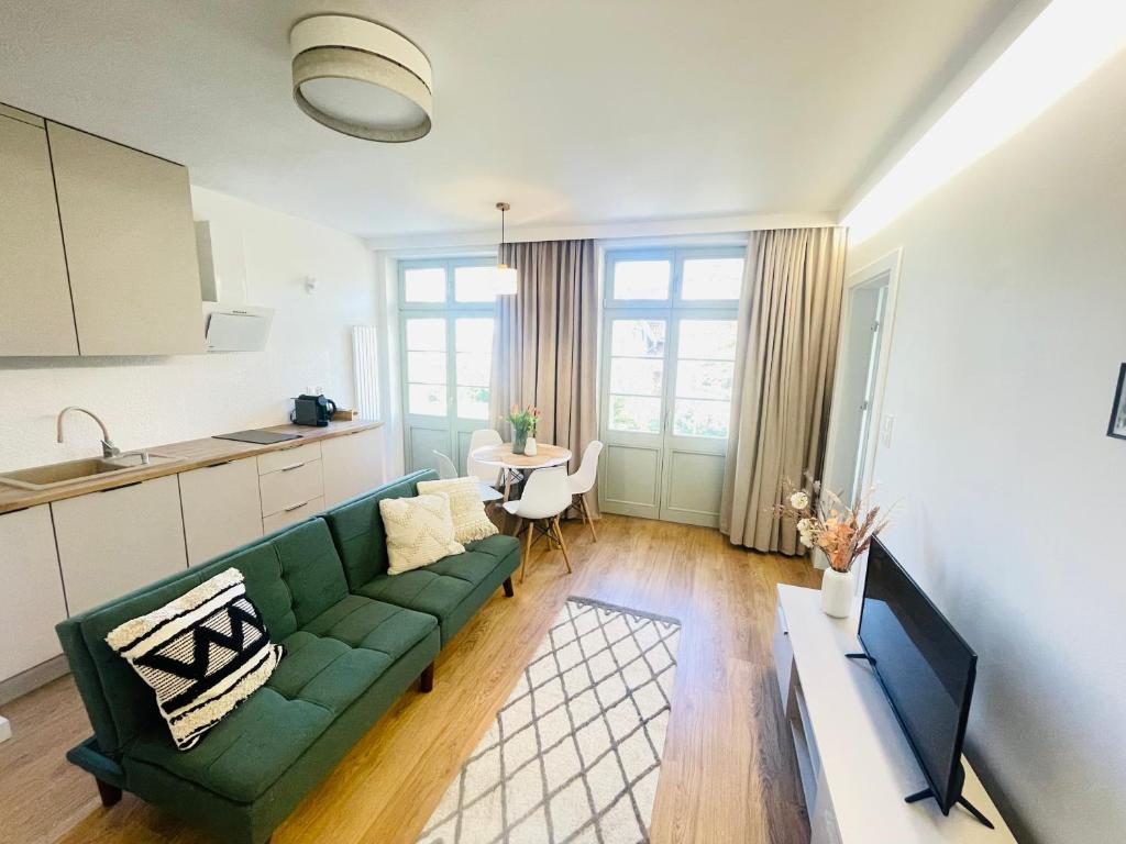 a living room with a green couch and a kitchen at Sopot Modern Apartments 3 in Sopot