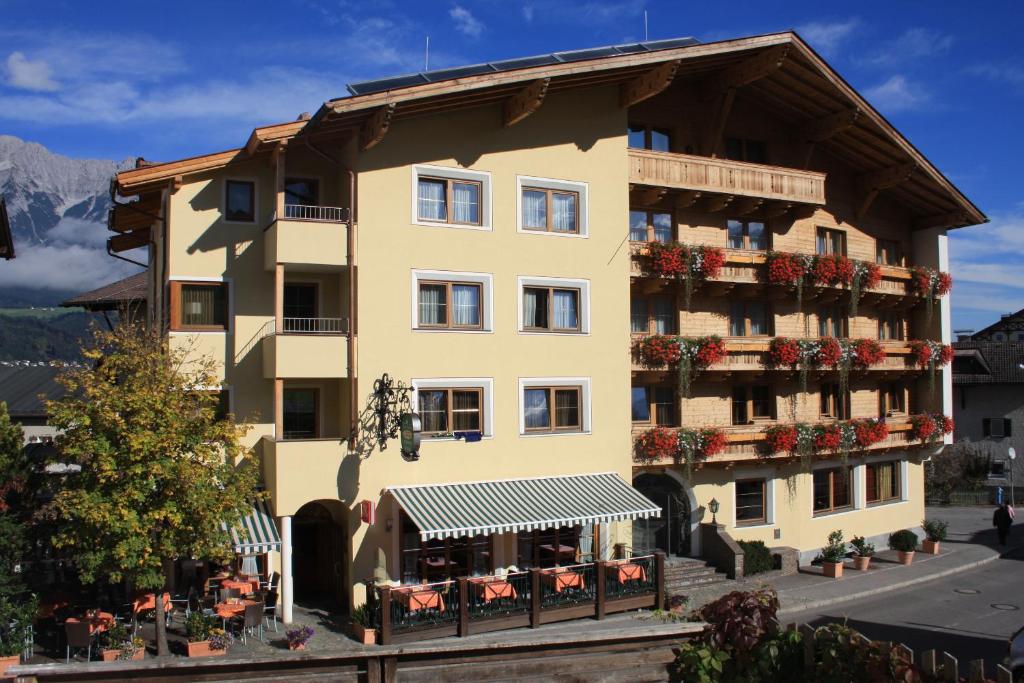 ein großes gelbes Gebäude mit Blumen auf den Balkonen in der Unterkunft Hotel Rettenberg in Kolsass