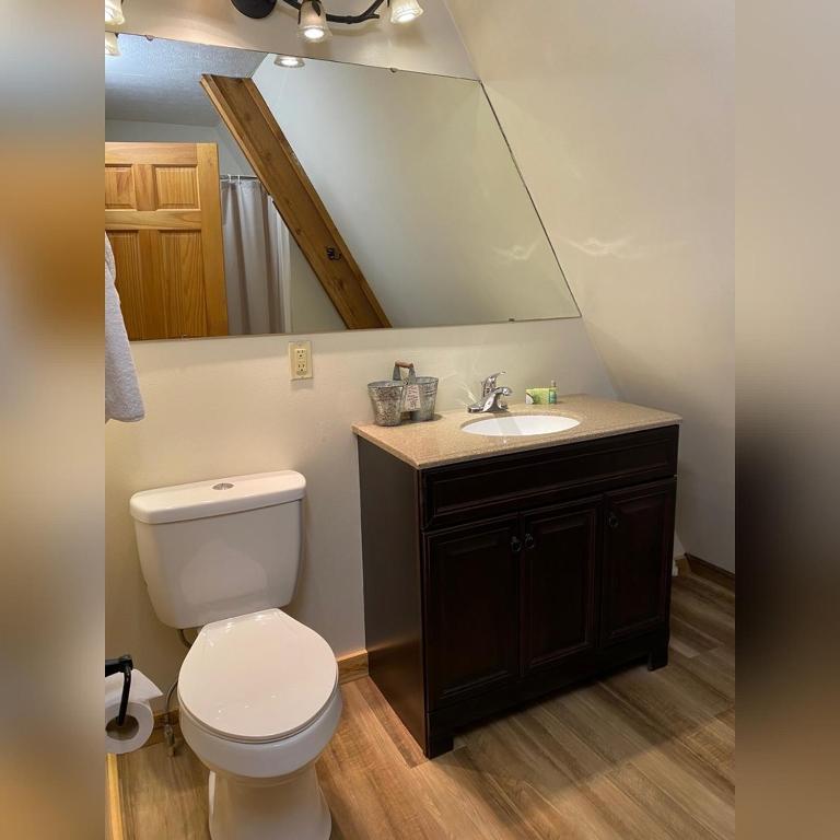 a bathroom with a toilet and a sink with a mirror at A-Frame #16 - by The Chalets in Logan