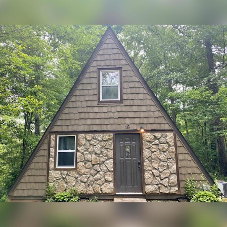 a small house with a stone wall at A-Frame #18 - by The Chalets in Logan