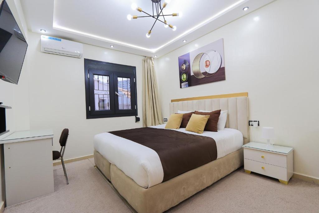 Duplex familial 3 chambres au cœur de la Corniche de Tanger في طنجة: غرفة نوم بها سرير ومكتب وتلفزيون