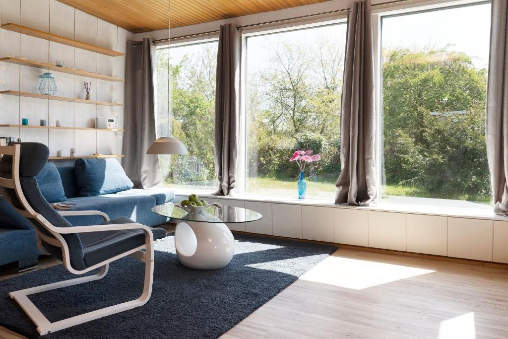 a living room with a blue couch and a large window at Zwergenhaus mit Meeresrauschen in Grömnitzerhagen