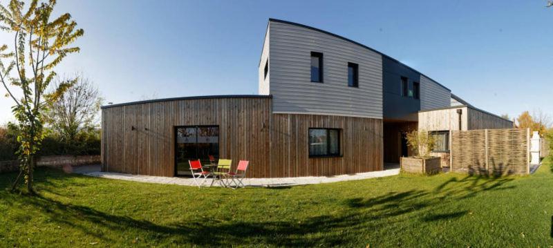 une maison en bois avec deux chaises rouges dans une cour dans l'établissement Gîte Noir Lapin, à Lesquin