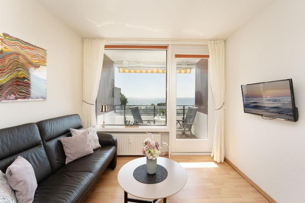 ein Wohnzimmer mit einer schwarzen Ledercouch und einem Tisch in der Unterkunft Haus Meeresblick Wohnung 79 in Kellenhusen