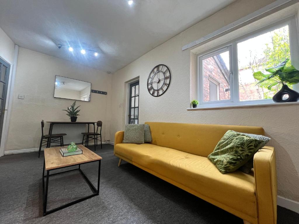 a living room with a yellow couch and a clock at Spacious House Close to Central Manchester With Free Parking in Manchester