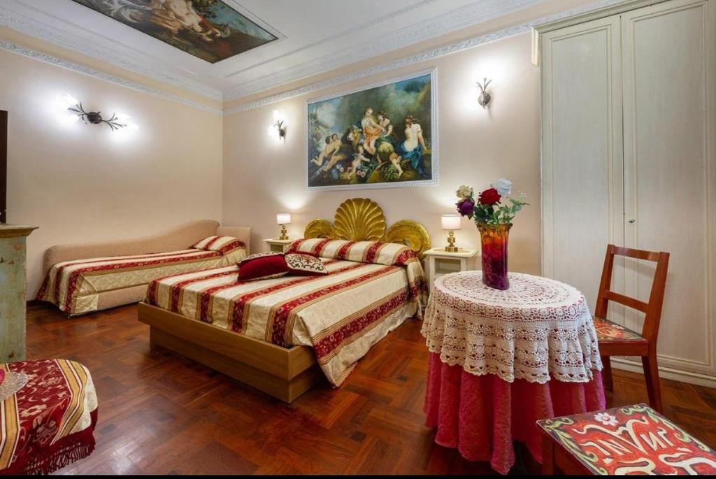 a bedroom with two beds and a table and a painting at Sancta Scala in Rome