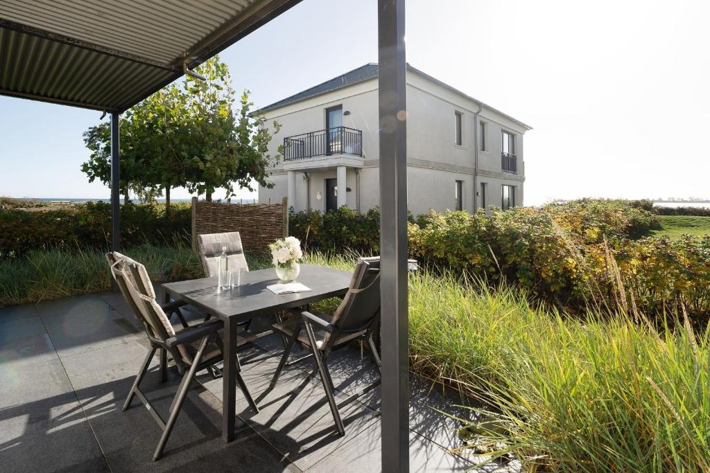 a table and chairs on a patio in front of a house at Strandresidenz Vogelflug App 8 in Fehmarnsund