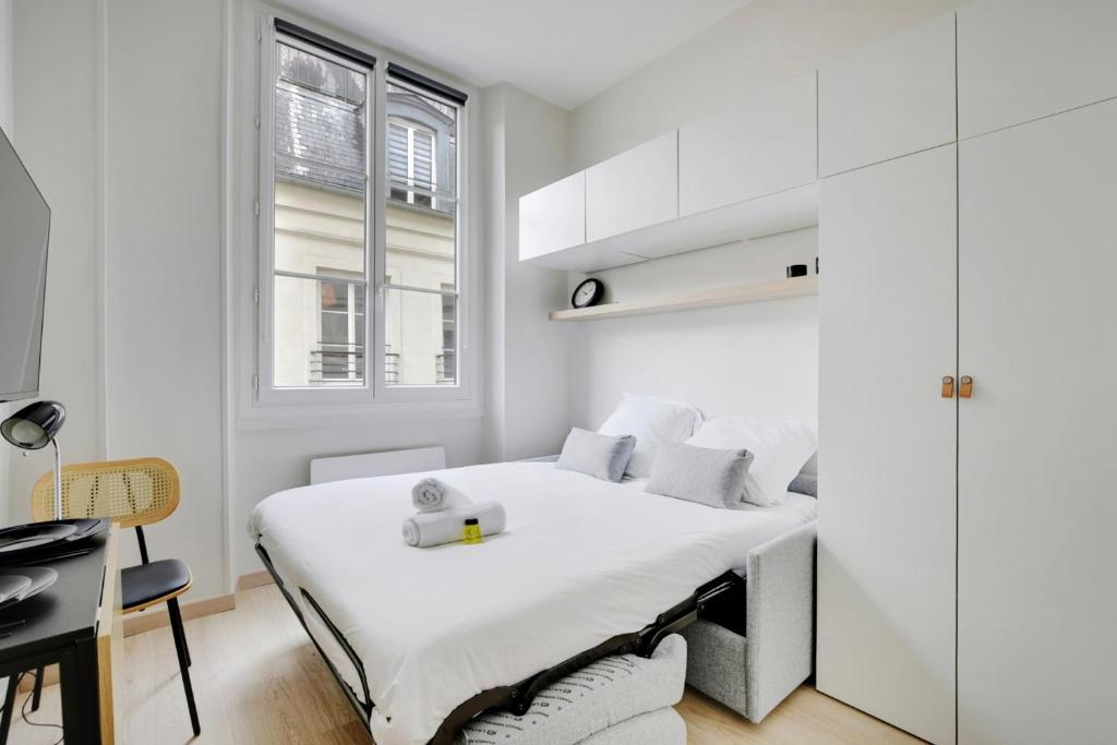 une chambre blanche avec un lit et un bureau dans l'établissement BUCCI - SAINT GERMAIN Charming apartment, à Paris