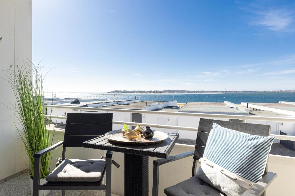 a table and chairs on a balcony with a view of the ocean at Aloha Suite in Fehmarn