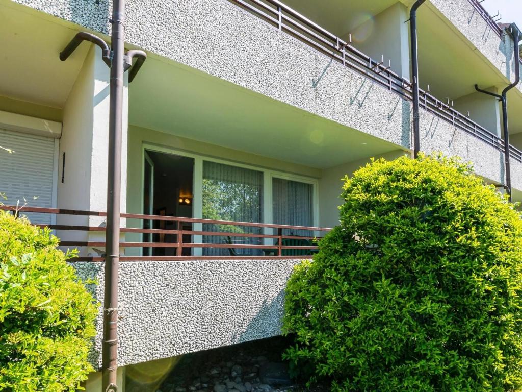 a house with a balcony with bushes in front of it at Waldstraße 2 Ferienwohnung Volkenborn in Kellenhusen