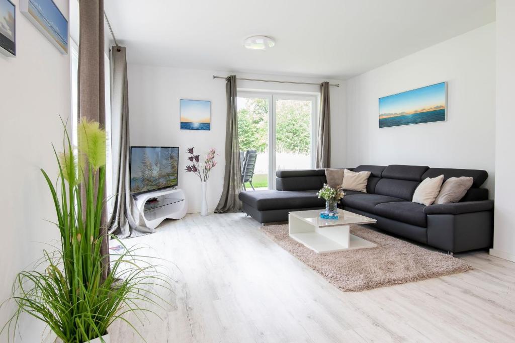 a living room with a black couch and a tv at Wohnung 2 in Haffkrug